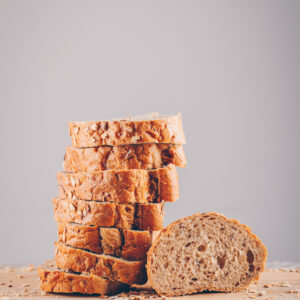 Side view sliced bread in cutting board on wooden table and gray background. vertical